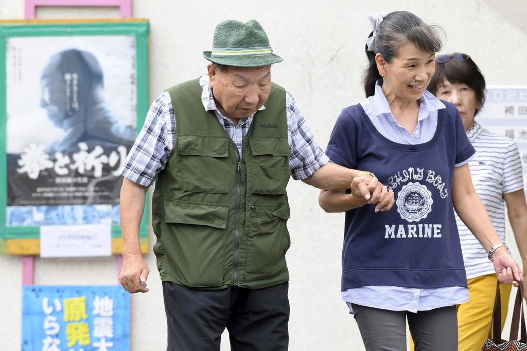Iwao Hakamada, left, 88-year-old former boxer who has been on death row for nearly six decades after his murder conviction that his lawyers said was based on forced confession and fabricated evidence, is helped by a supporter as he goes for a walk in Hamamatsu, Shizuoka prefecture, central Japan Wednesday, Sept. 25, 2024.