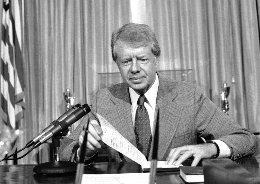 President Jimmy Carter flips through notes at the Oval Office of the White House in Washington, Nov. 1, 1978, as he talks by telephone to an anti-inflation forum in St. Louis. Earlier in the morning Carter announced plans to prop up the ailing dollar aboard. 