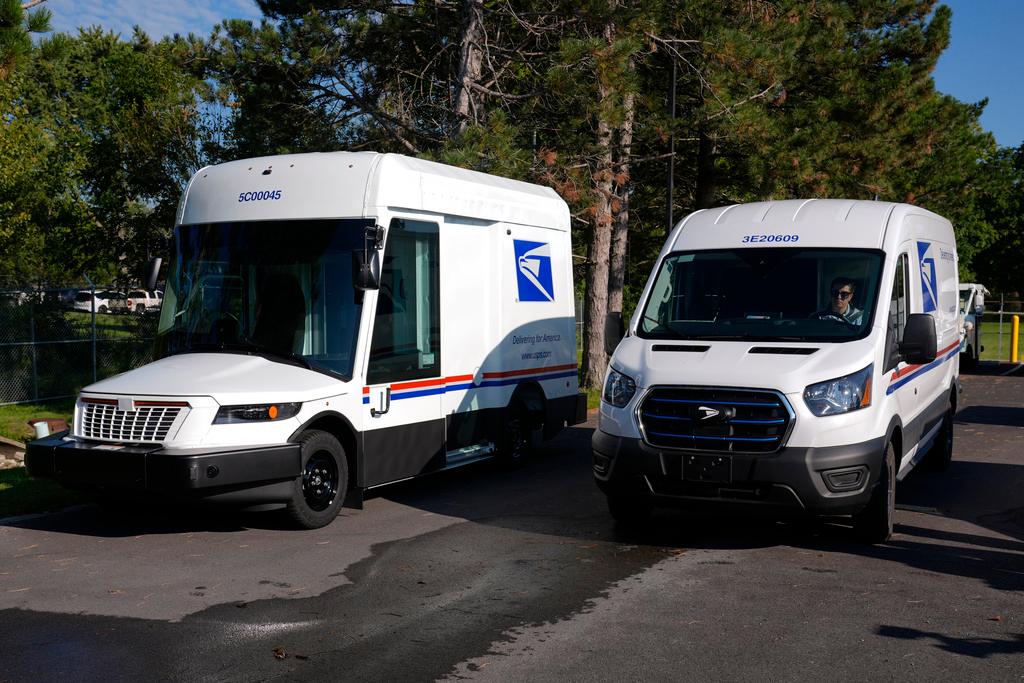 The U.S. Postal Service's next-generation delivery vehicle, left, is displayed as one new battery electric delivery trucks leaves the Kokomo Sorting and Delivery Center in Kokomo, Ind.