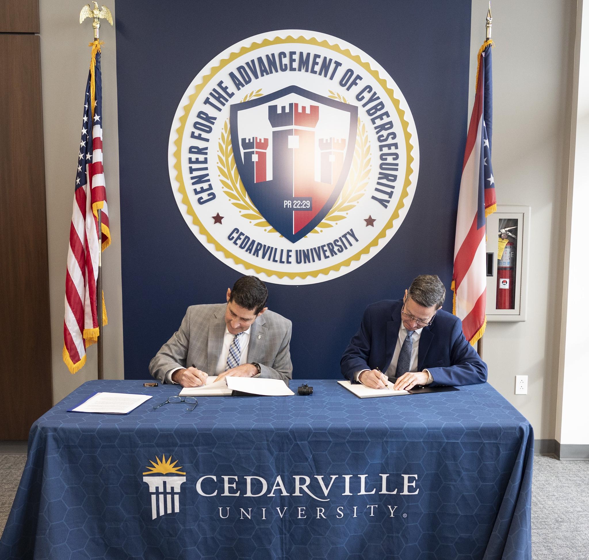 Robert Fookes, SES, Director of Engineering and Technical Management and Chief Engineer, Air Force Material Command at Wright Patterson Air Force Base, signs the official education partnership agreement with Cedarville University. He is joined by Dr. Thomas Mach, vice president for academic affairs at Cedarville 