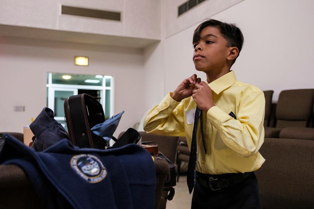 Giovanni Vazquez puts on his tie during a rehearsal for a secular orchestra hosted by the New Hope Presbyterian Church 