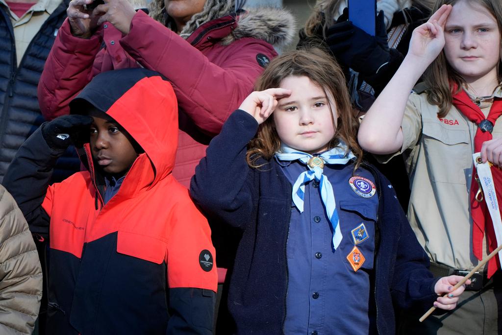 Children watch as the hearse carrying the flag-draped casket of former President Jimmy Carter pauses outside the State Capitol in Atlanta