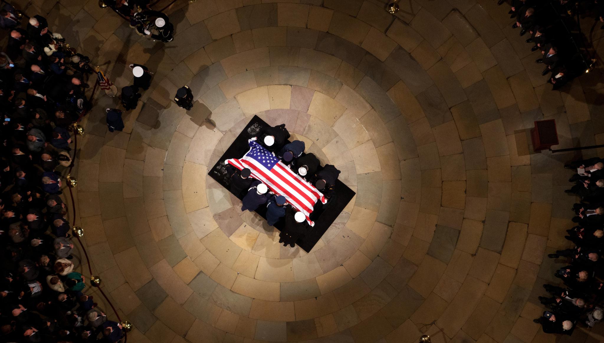 Birds-eye view of the casket draped in the American flag with members of Congress surrounding it