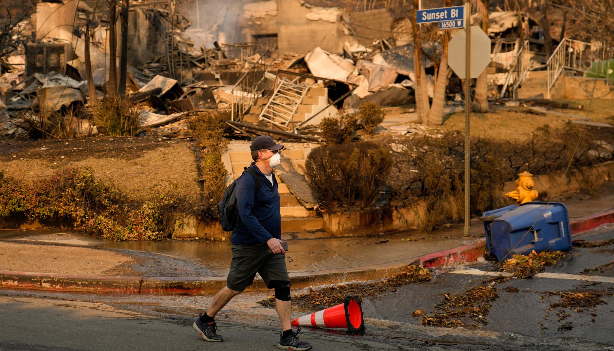 Man walks by fire-destroyed house on Sunset Blvd.