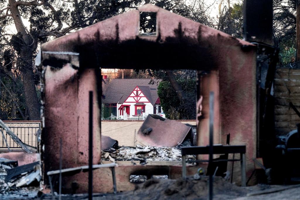 A home destroyed by the Eaton Fire stands in front of a home that survived in Altadena. Calif.