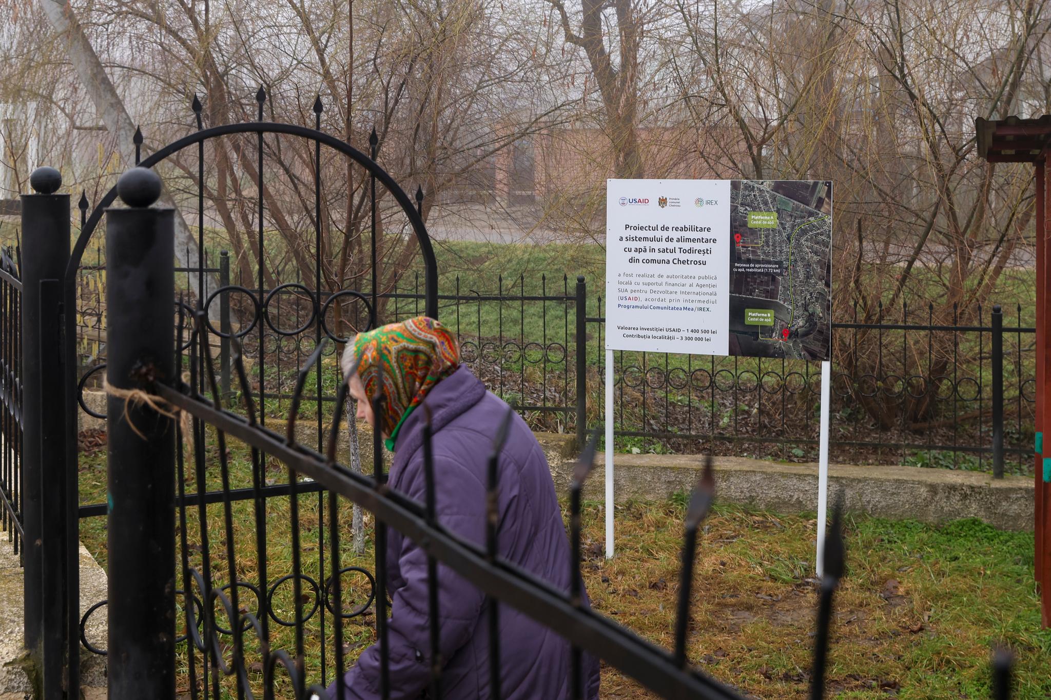 Elderly woman walking outside with a bright scarf over her head