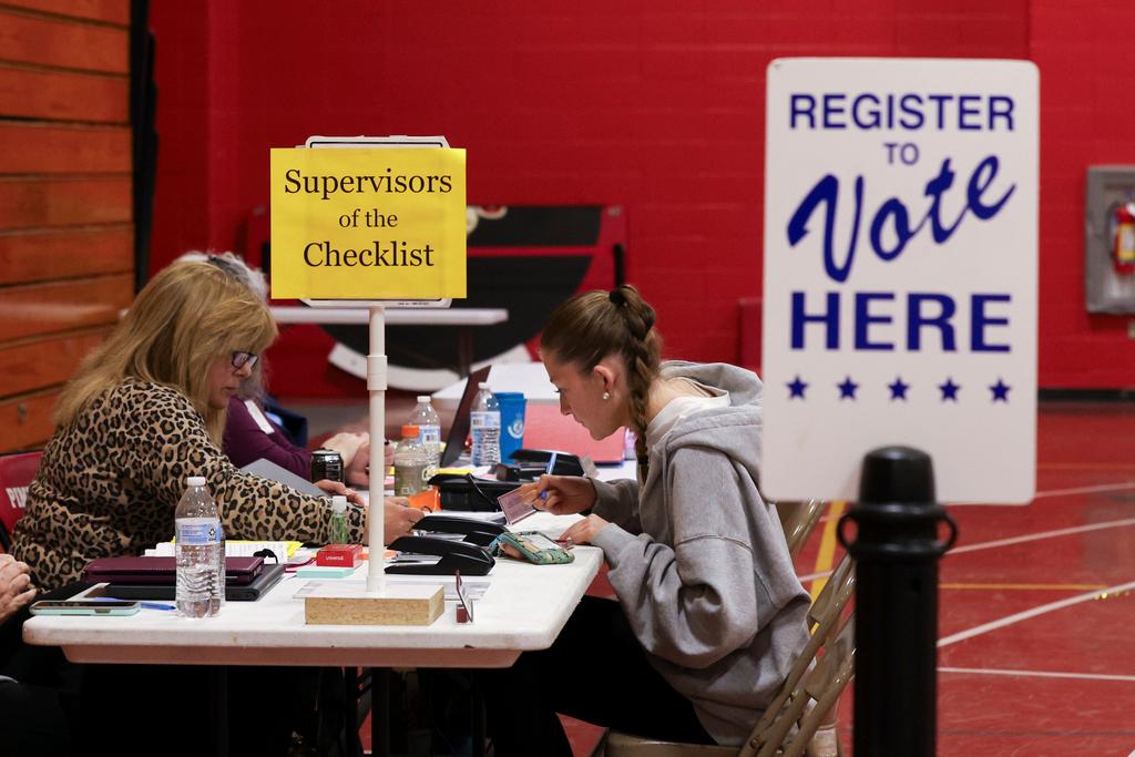 Supervisor of the Checklist for the State of New Hampshire Leslie Dombroski, left, registers Elise Collins, 18, to vote in Derry, N.H.