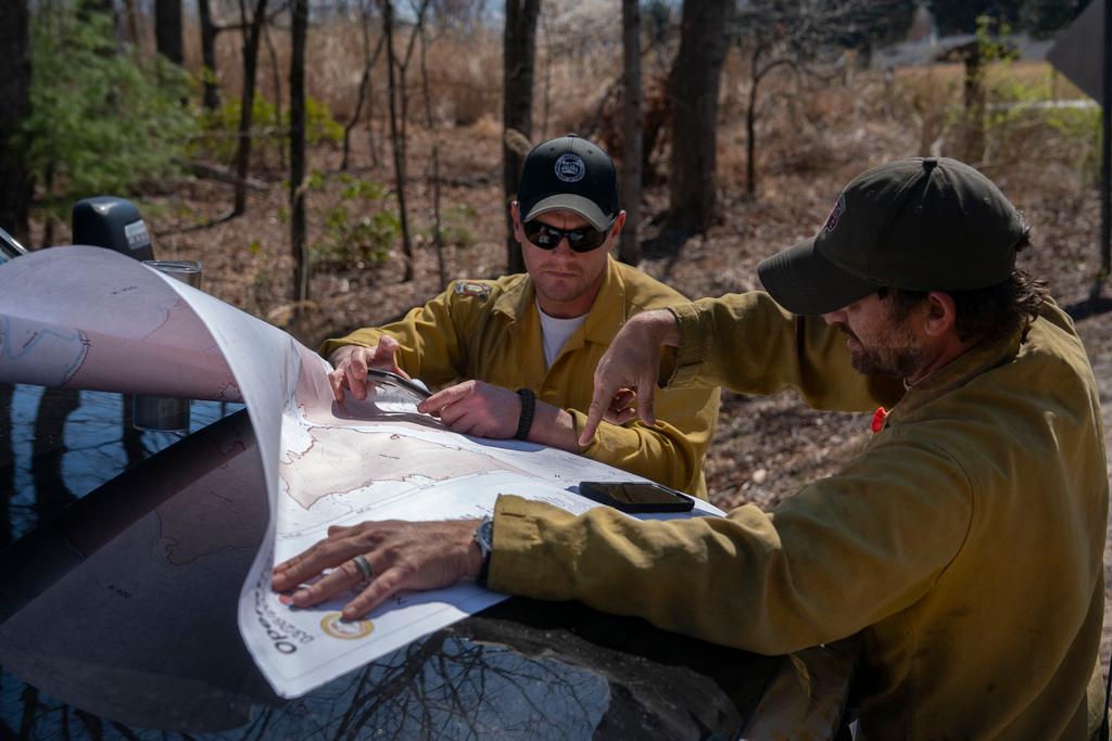 Firefighters look at a map as the Black Cove Fire burns near Saluda, N.C.