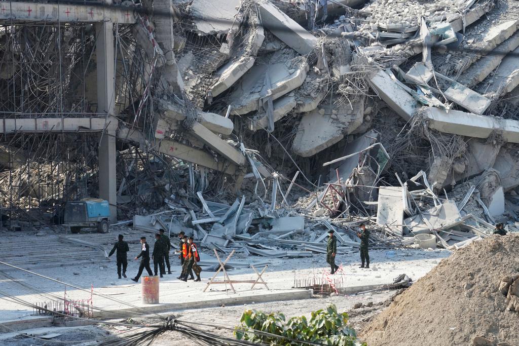 Rescuers walk at the site of a high-rise building under construction that collapsed after a 7.7 magnitude earthquake in Bangkok