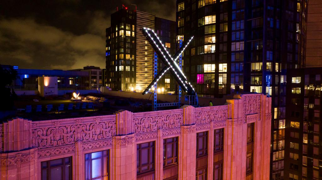Workers install lighting on an "X" sign atop the company headquarters, formerly known as Twitter, in downtown San Francisco