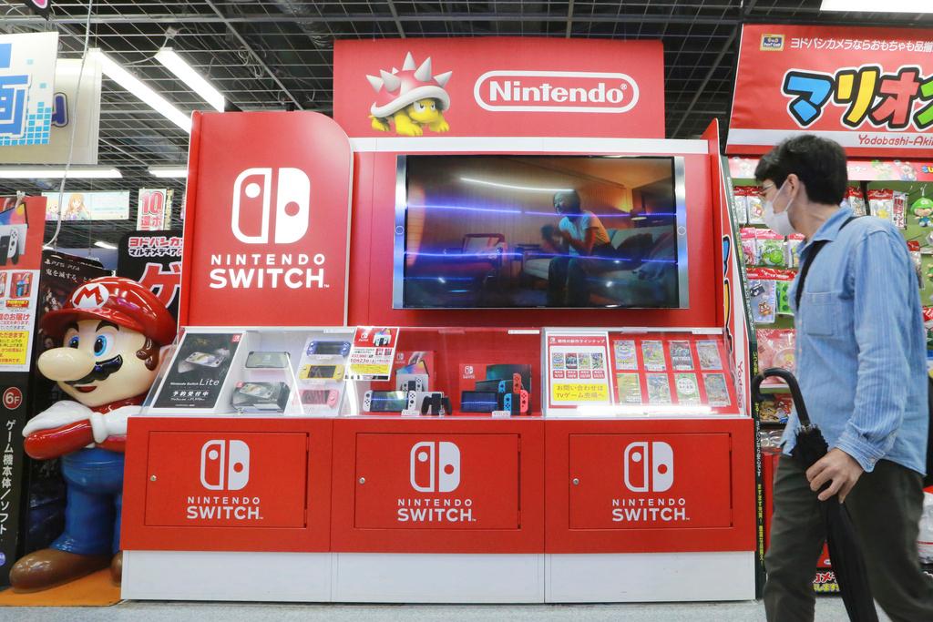 FILE - A man walks by a Nintendo Switch display at an electronics retail chain store in Tokyo, on Oct. 13, 2021. 