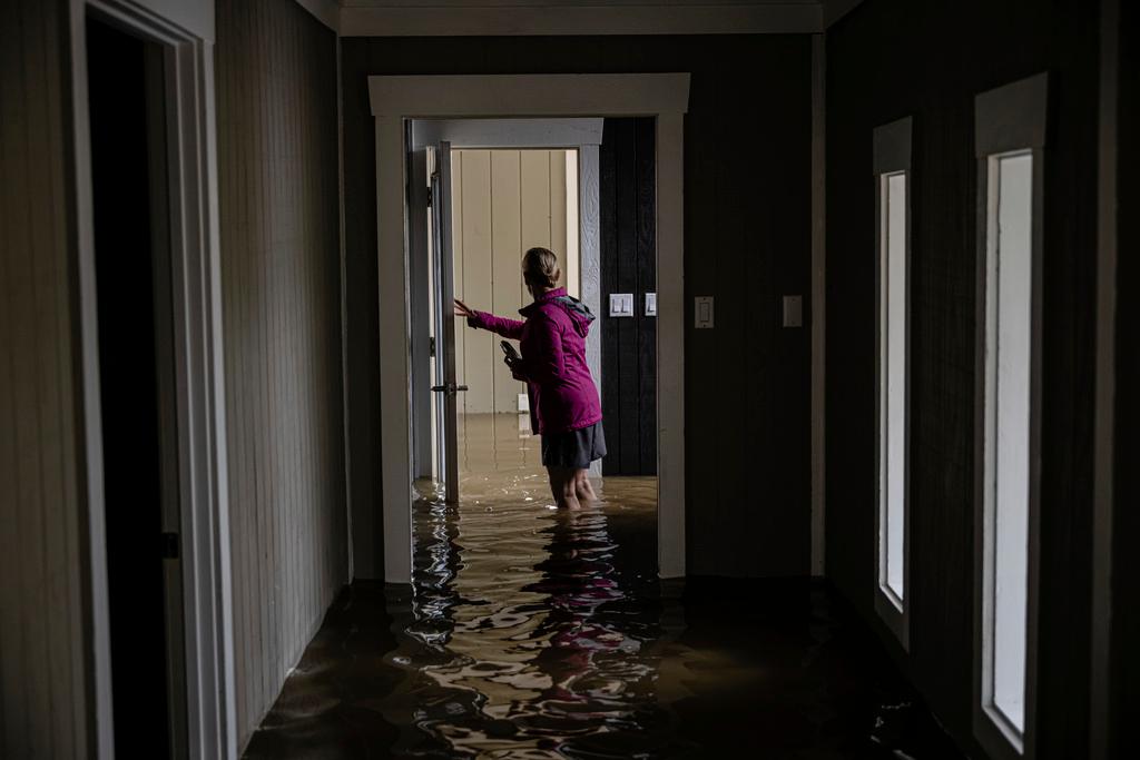 Carole Smith walks through her flooded home in Frankfort, Ky.