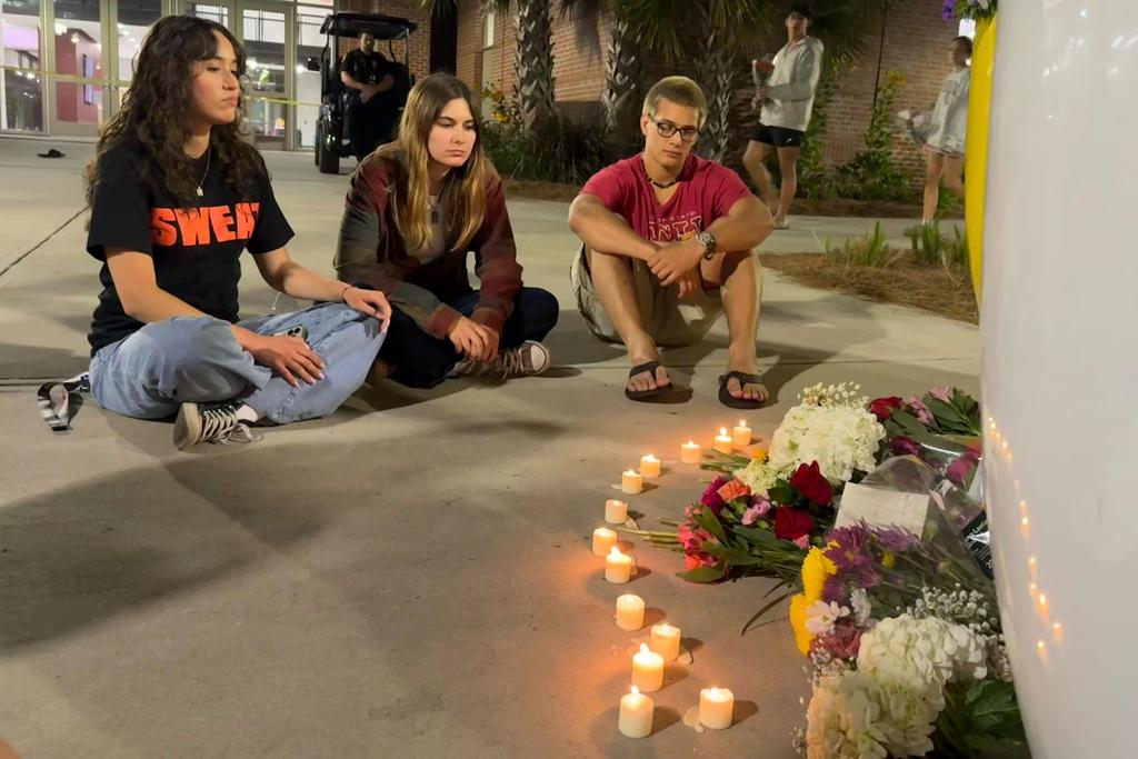 People sit in front of a makeshift memorial outside the student union at Florida State University