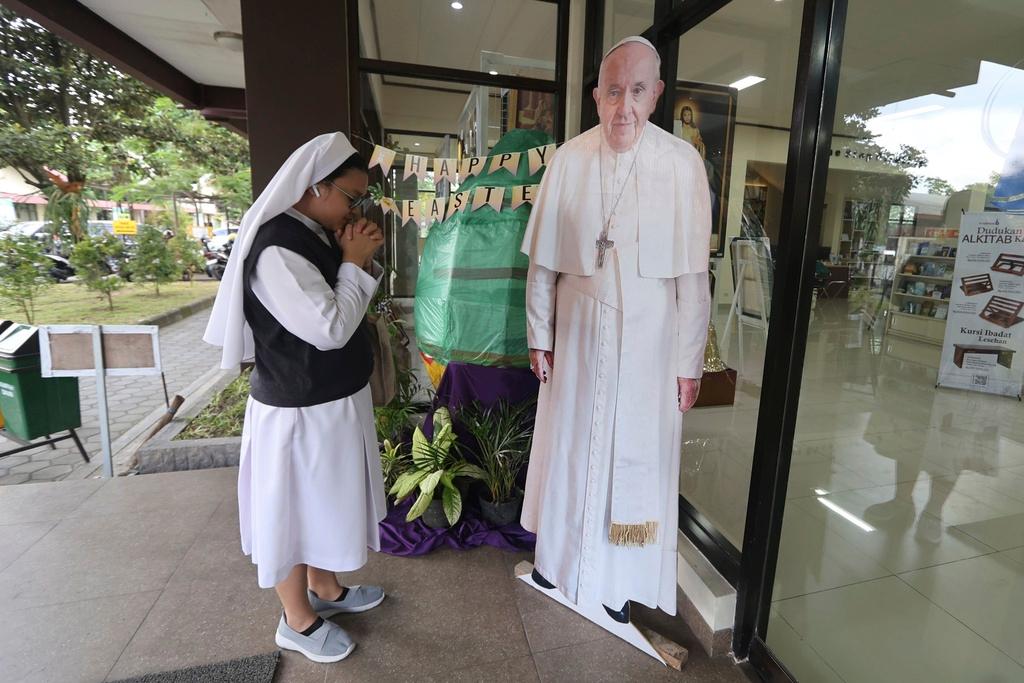 A Catholic nun prays in front of a cutout of Pope Francis in Yogyakarta, Indonesia