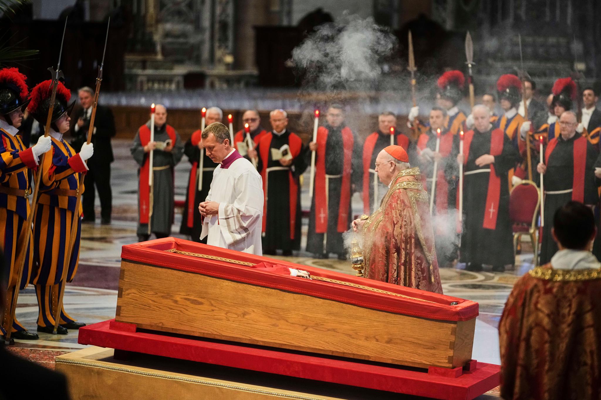 A wooden coffin containing Pope Francis surrounded by Cardinals and priests