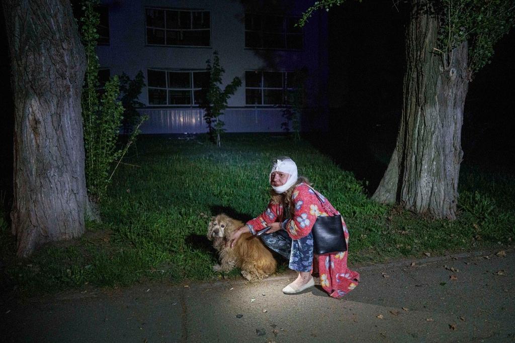 An injured woman sits with her dog near a house destroyed by a Russian airstrike in a residential neighborhood in Kyiv