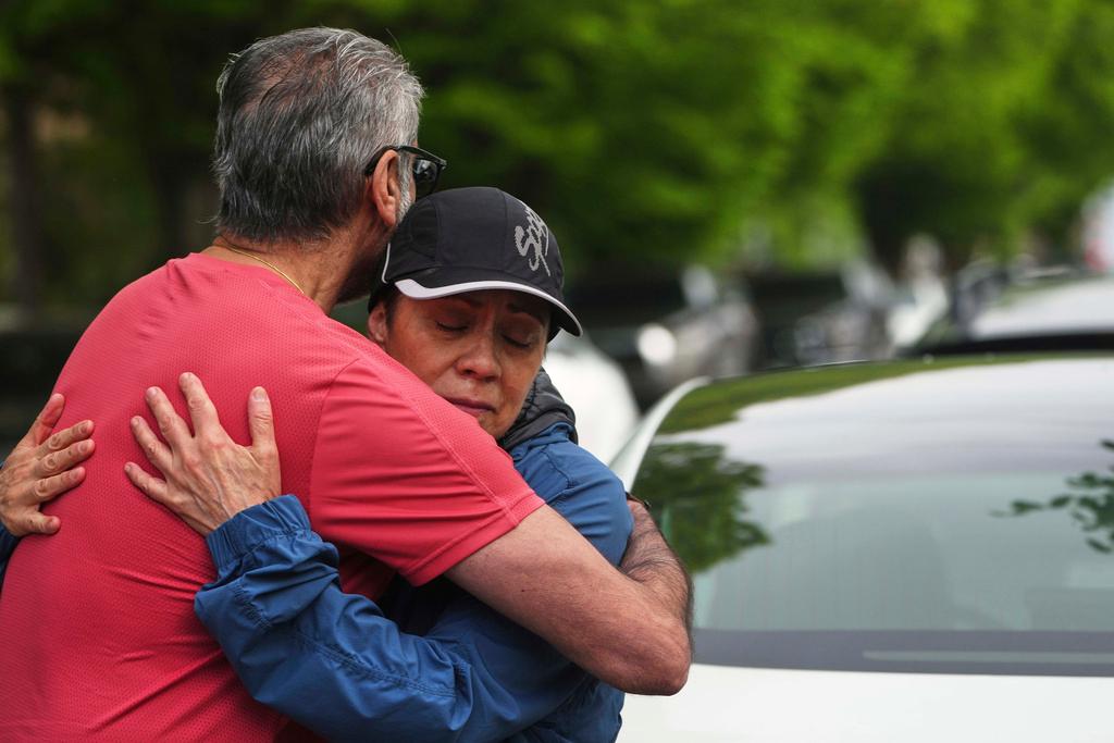 Esperanza Bermudez, facing, who lives across the street from the scene, is comforted 