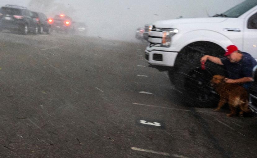 A man and his dog duck behind a truck as the storm hits at Fort Cherry High School in McDonald, Pa.