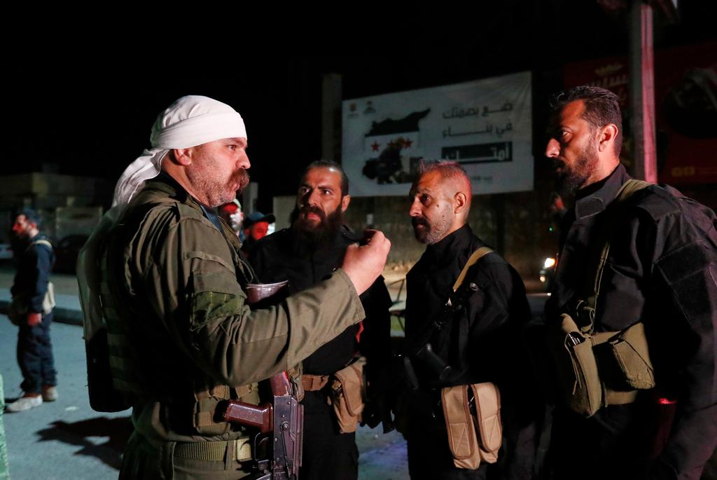 A Druze gunman, left, speaks with Syrian security forces 