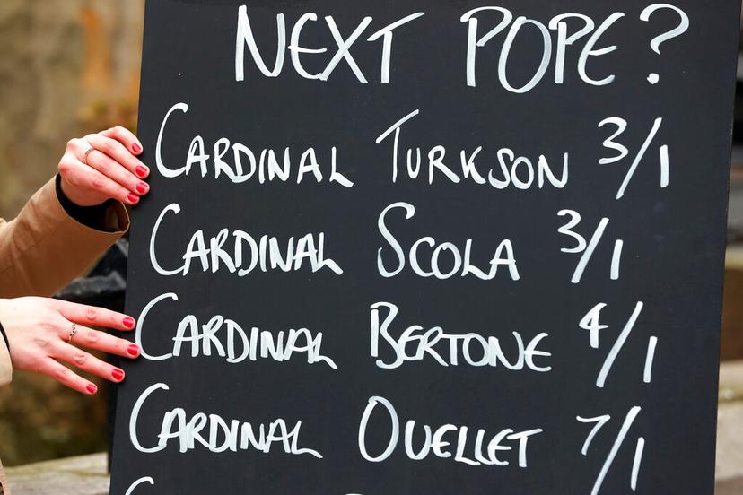 Jessica Bridge, a spokesperson with a betting company, poses for members of the media, next to bookies' board with odds regarding the possible new Pope