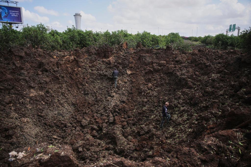 Israeli security forces inspect a crater at the site where the Israeli military said a projectile fired by Yemen's Houthi rebels landed in the area of Ben Gurion International Airport near Tel Aviv