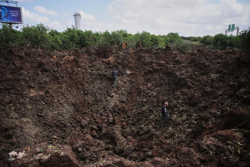 Israeli security forces inspect a crater at the site where the Israeli military said a projectile fired by Yemen's Houthi rebels landed in the area of Ben Gurion International Airport near Tel Aviv