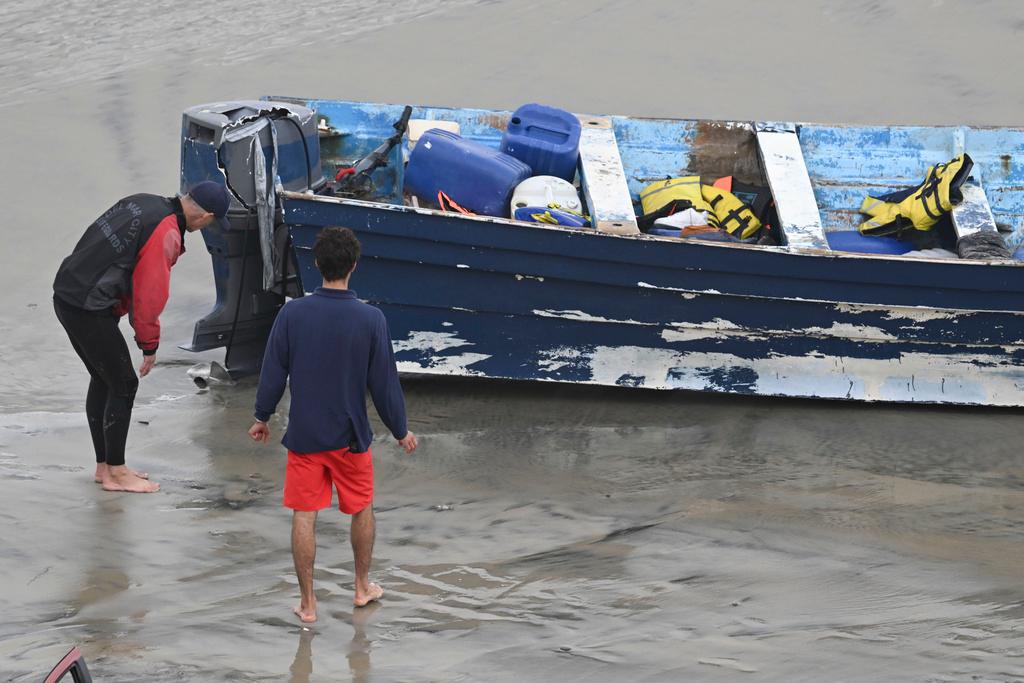 Del Mar lifeguard looks over a capsized boat at Torrey Pines State beach in San Diego