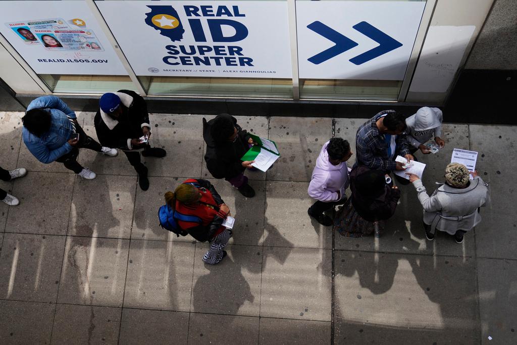 An employee, right, checks on necessary documents as people line up to apply for Real ID at a Real ID Supercenter in downtown Chicago