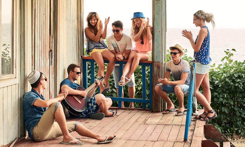 Seven people gathering and listening to guitar player