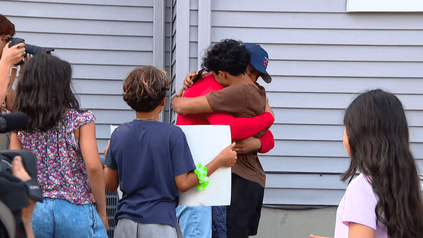 Boy hugs his dad with crowd surrounding him.