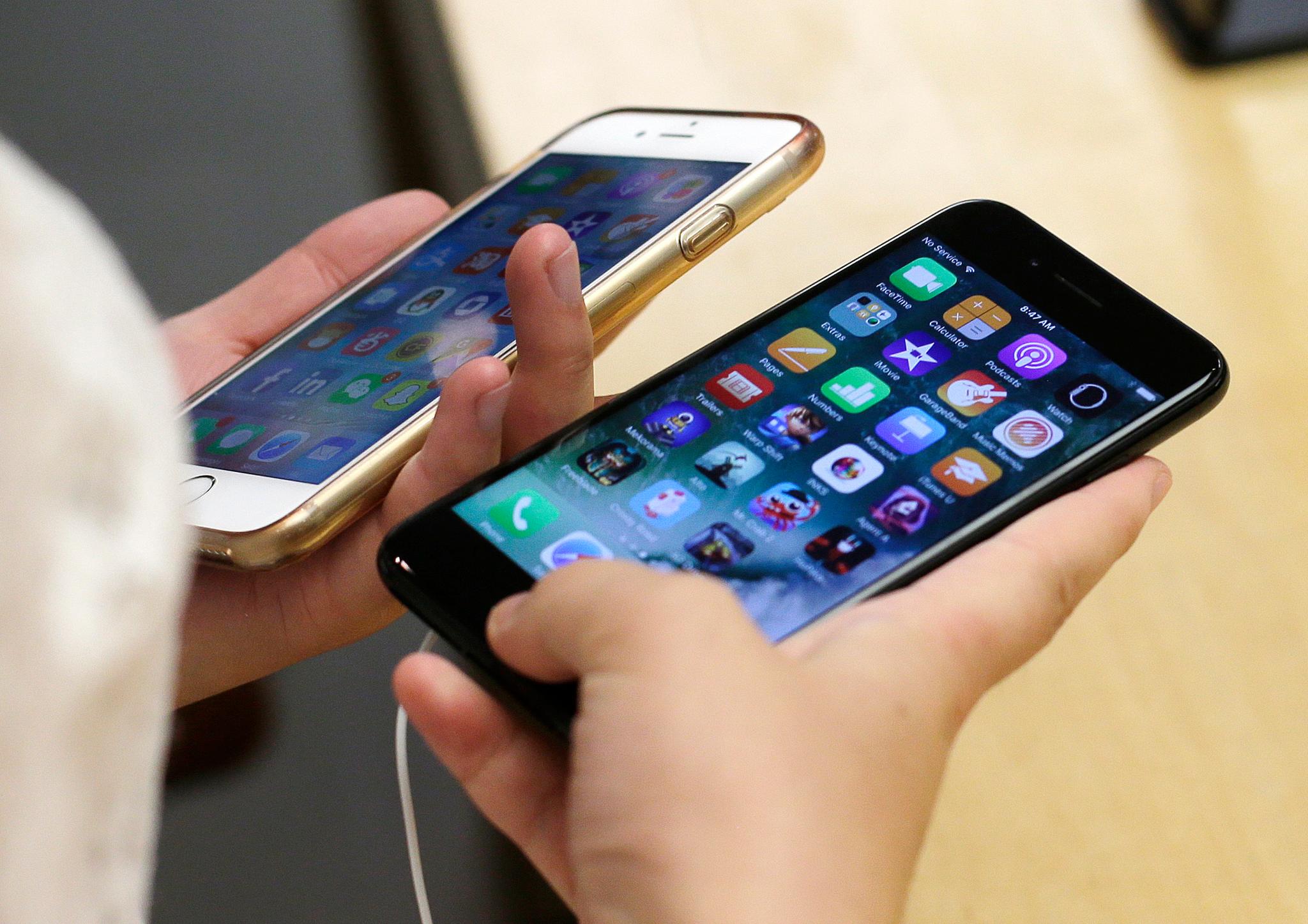 Person holding iPhone 6 and iPhone 7 smartphones
