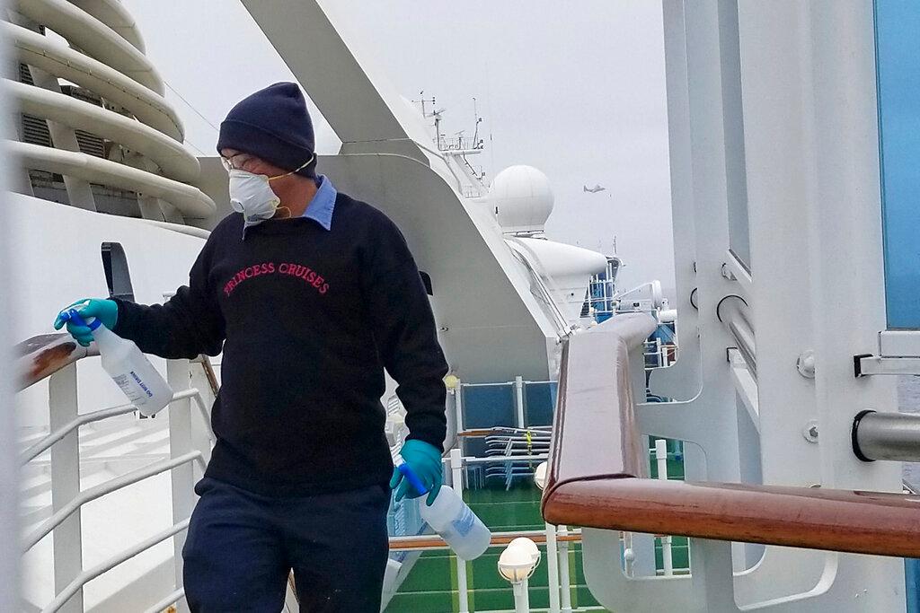 A cruise ship worker cleans a railing on the Grand Princess 
