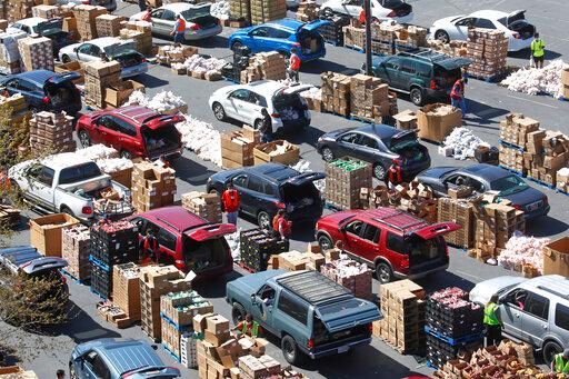Cars line up for food at the Utah Food Bank's mobile food pantry at the Maverik Center