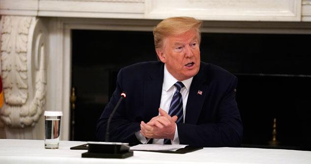 President Trump in a blue suit and striped tie in State Dining Room of the White House with microphone in front of him