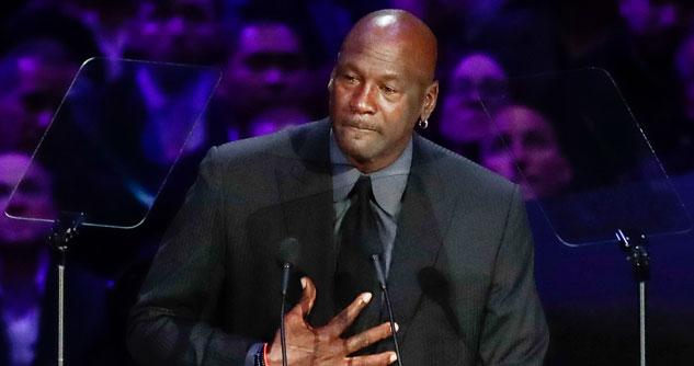 Michael Jordan in a dark suit with a microphone in front of him