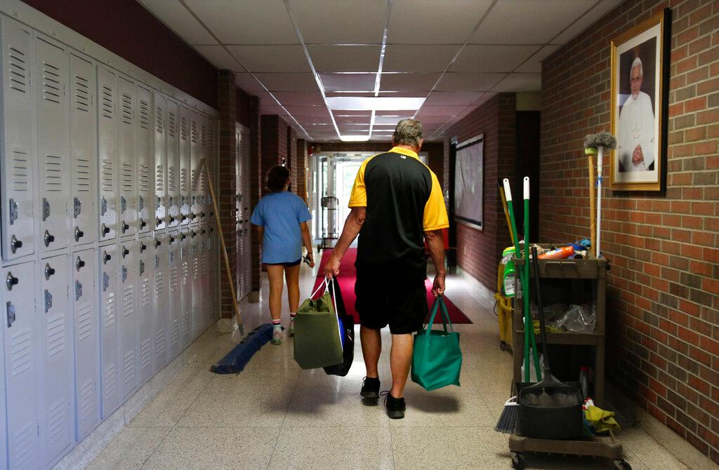 Cesa Pusateri, 12, and her grandfather, Timothy Waxenfelter, principal of Quigley Catholic High School, leave with his collection of speech and debate books after the recent closure of the school in Baden, Pa.