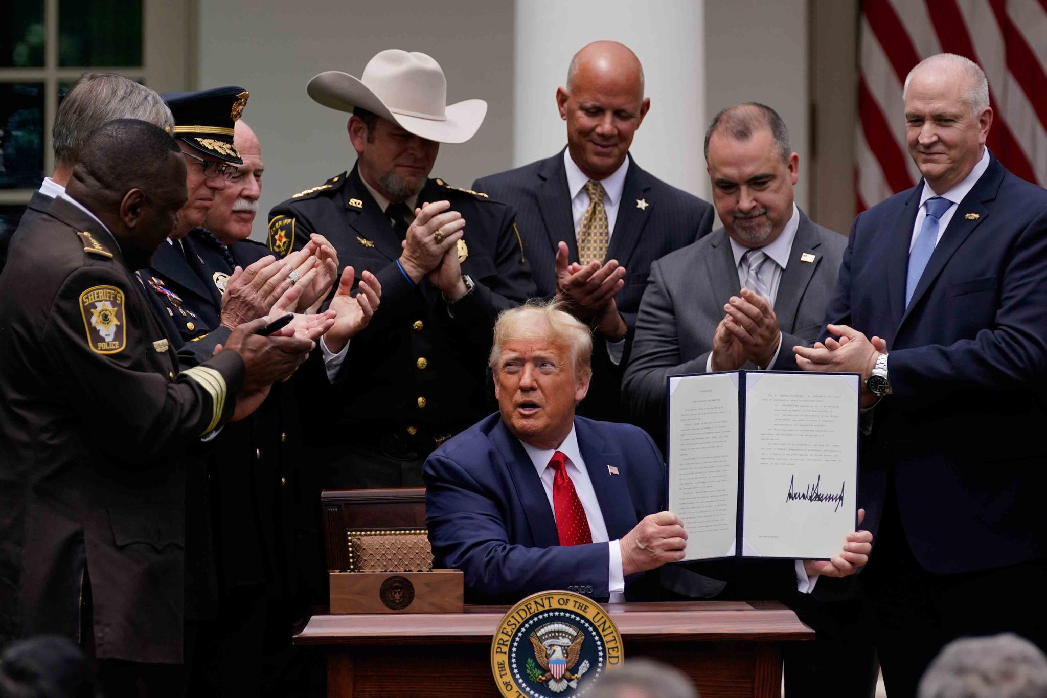Law enforcement officials applaud after President Donald Trump signed an executive order on police reform, in the Rose Garden of the White House
