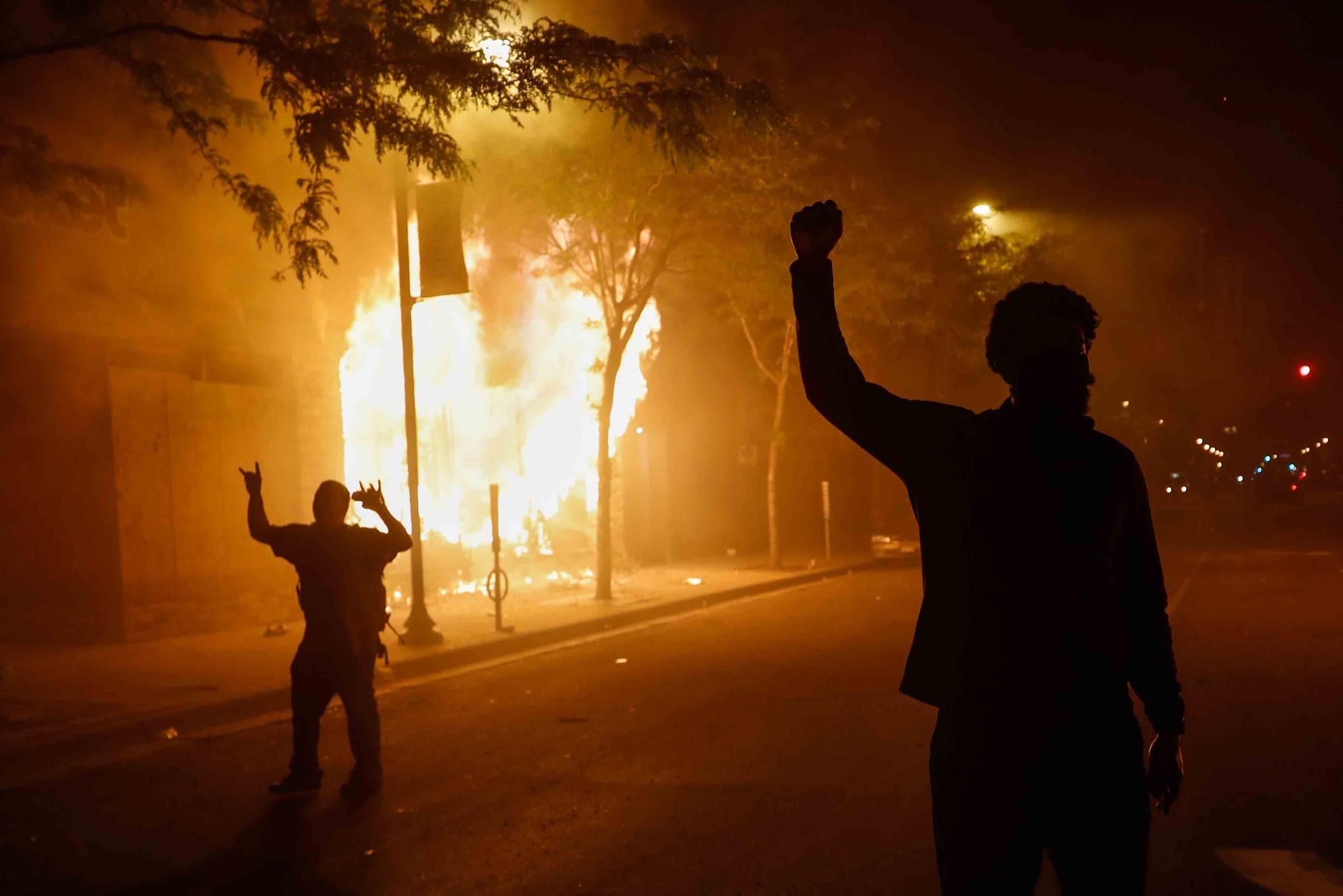 Protesters react along Chicago Avenue as fires rage along a strip of businesses, early Saturday, in Minneapolis