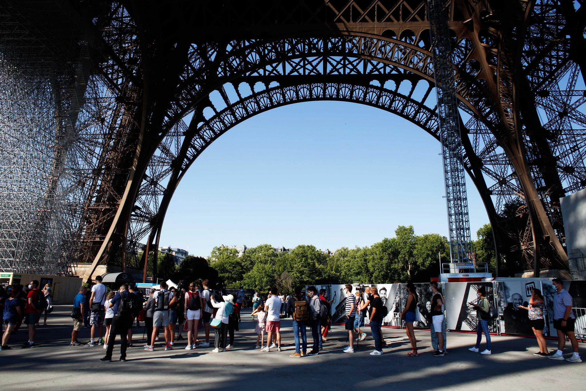 People wait in line under the Eiffel Tower