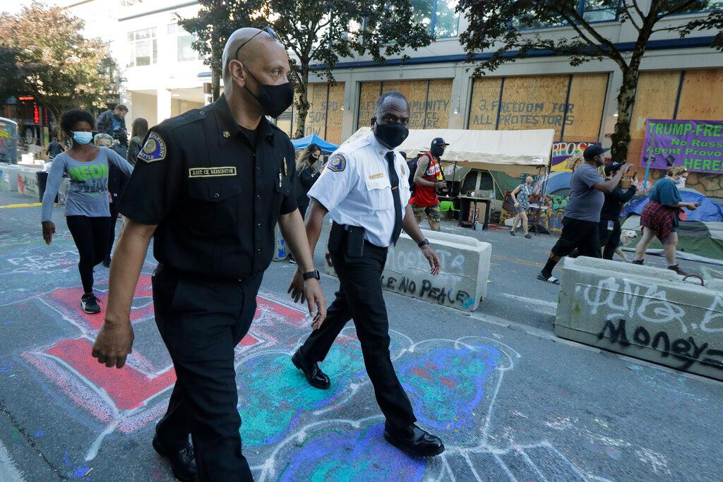 Seattle Fire Chief Harold Scoggins, right, and Assistant Chief Willie Barrington, left, walk, Friday, June 26, 2020 inside the CHOP (Capitol Hill Occupied Protest) zone in Seattle. The officials were on hand to try and negotiate with protesters after workers and trucks from the Seattle Department of Transportation who had arrived with the intention of removing barricades were met with resistance. The area has been occupied by protesters since Seattle Police pulled back from their East Precinct building following violent clashes with demonstrators earlier in the month.