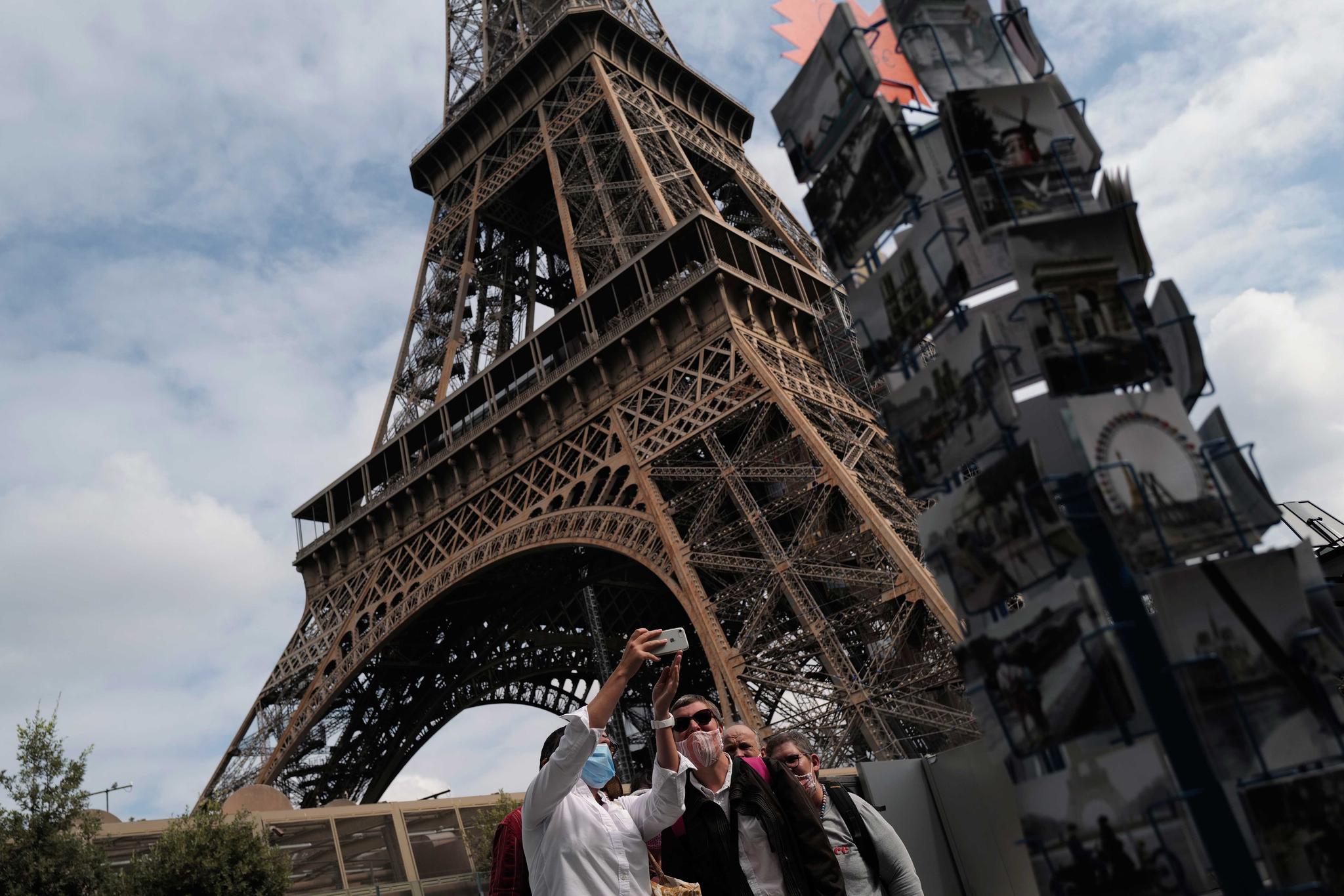 Visitors take a selfie at the main entrance of the Eiffel Tower