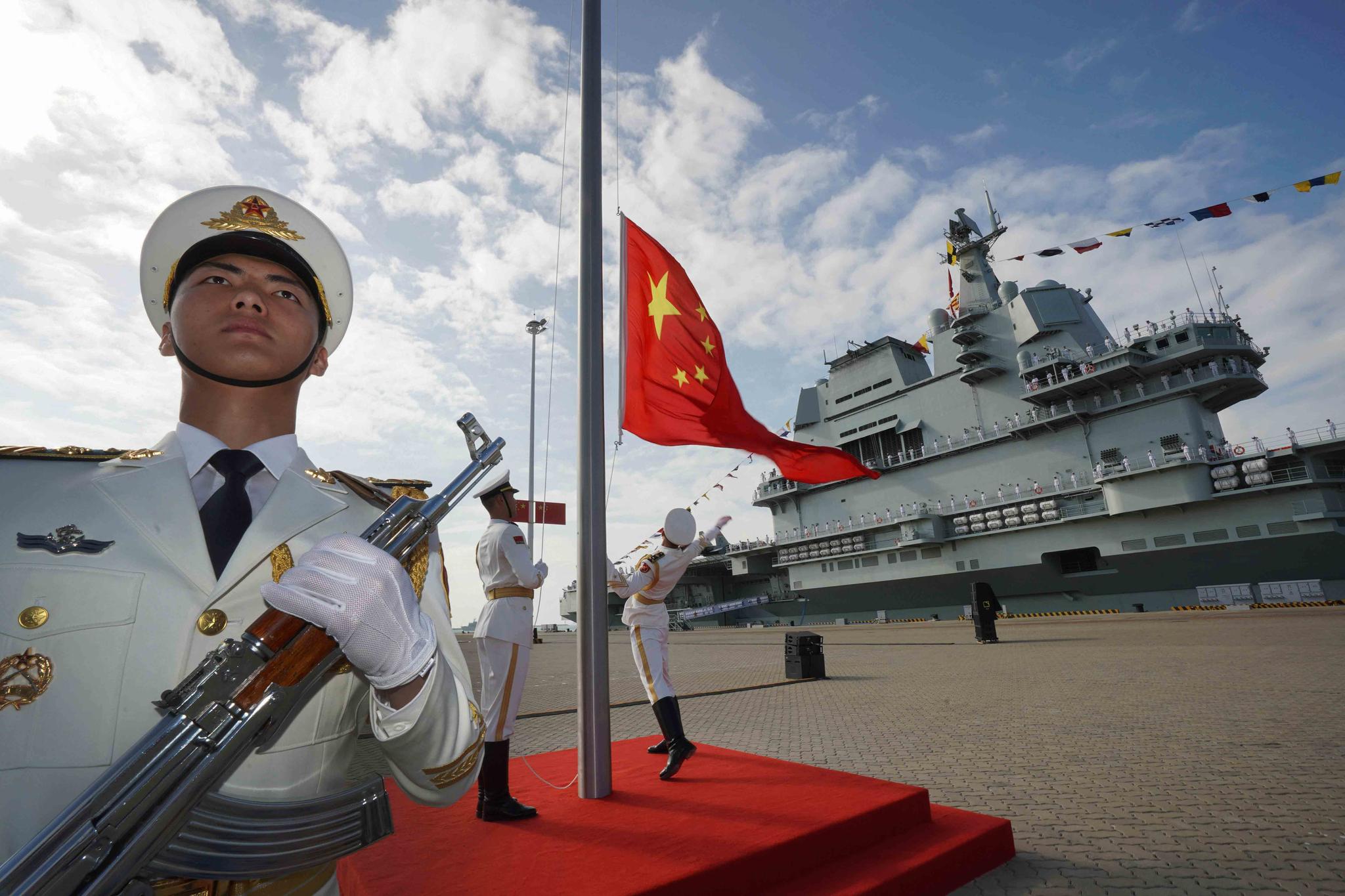 In this file photo taken Dec. 17, 2019 and released Dec. 27, 2019 by Xinhua News Agency, Chinese honor guard raise the Chinese flag during the commissioning ceremony of China's Shandong aircraft carrier at a naval port in Sanya, south China's Hainan Province.