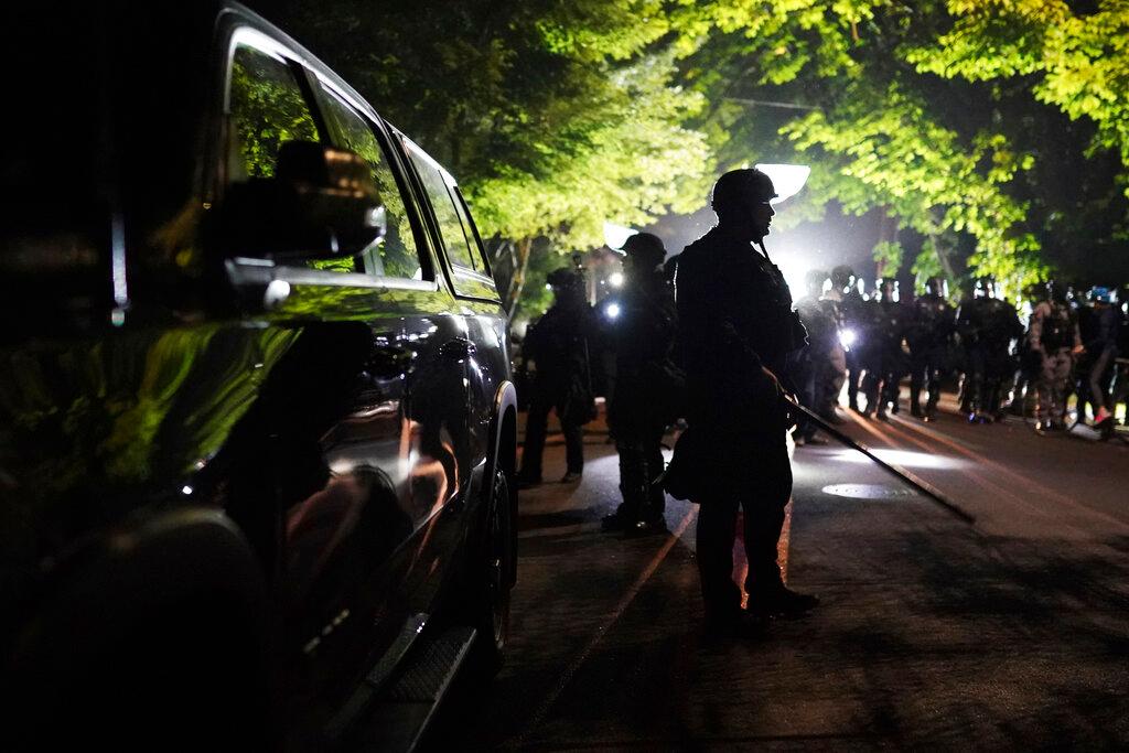 Portland police officers walk through the Laurelhurst neighborhood after dispersing protesters from the Multnomah County Sheriff's Office