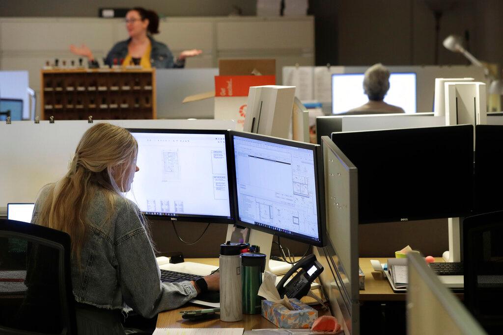 Architectural designer Erica Shannon, front, works at a computer 