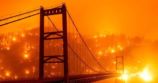 Bridge with fire in the hills behind them.