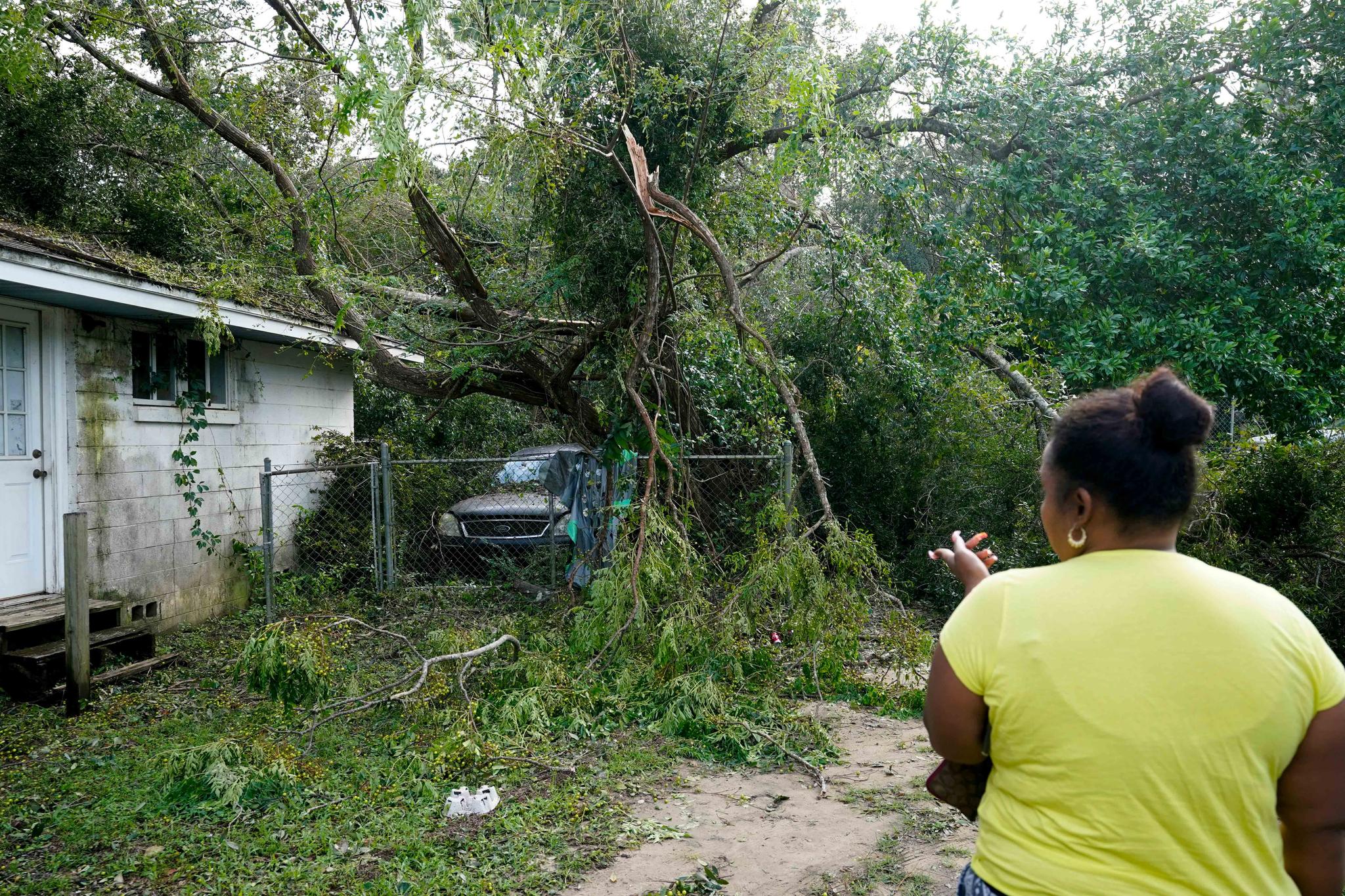 Woman looks over a neighbor's home that was damaged by Hurricane Sally