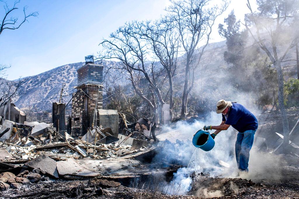Man pouring water on fire at burned property 