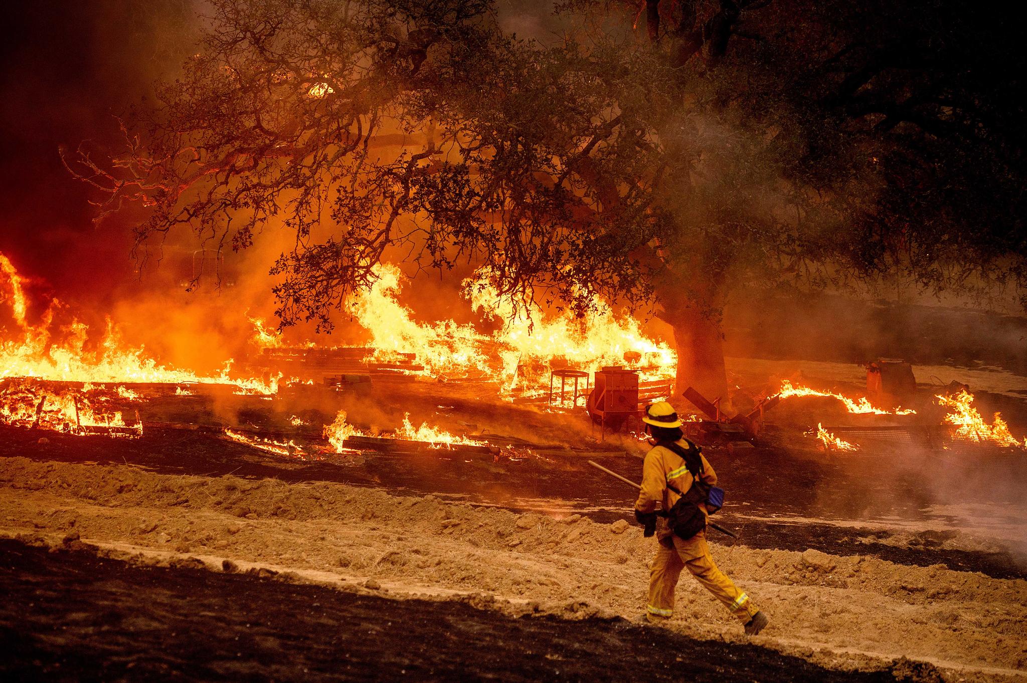 A firefighter passes flames while battling a wildfire