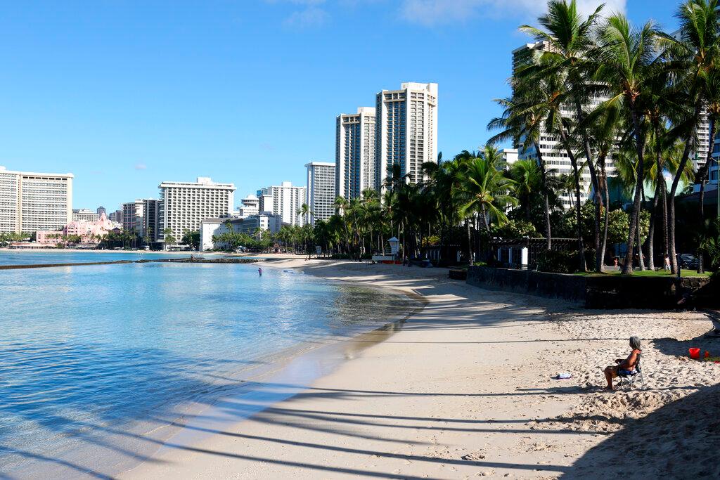 Man sits on a nearly empty Waikiki Beach in Honolulu