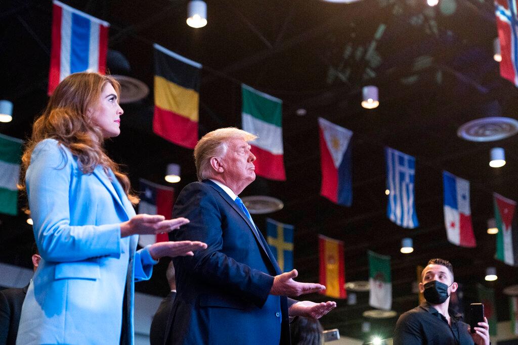 President Donald Trump closes his eyes as he accepts blessings as he attends church at International Church of Las Vegas, Counselor to the President Hope Hicks is at left